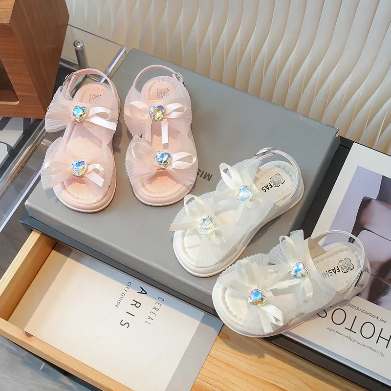 

Детские сандалии для девочек, новинка лета 2025 года, модная элегантная мягкая удобная универсальная пляжная обувь принцессы с милым бантом и стразами
