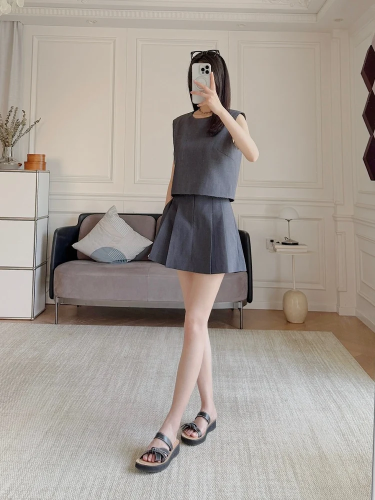 

Комплект из двух предметов: жилет из цветной тканой шерстяной смеси в клетку и плиссированная юбка. Модный летний наряд. Без бренда.