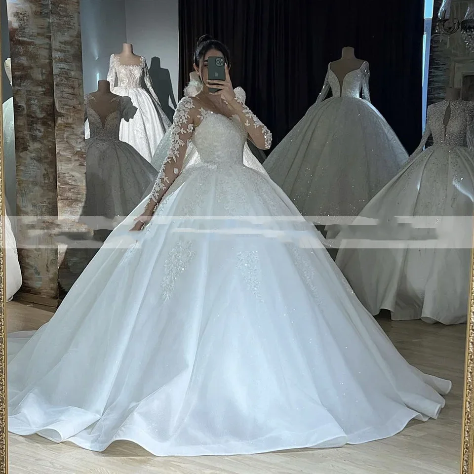 ชุดแต่งงานแบบบอลกาวน์สีขาวสั่งตัดพิเศษ คอทรงโอ แขนยาวเงางาม ประดับลูกไม้  กระโปรงยาวลากพื้น  ผูกเชือกด้านหลัง