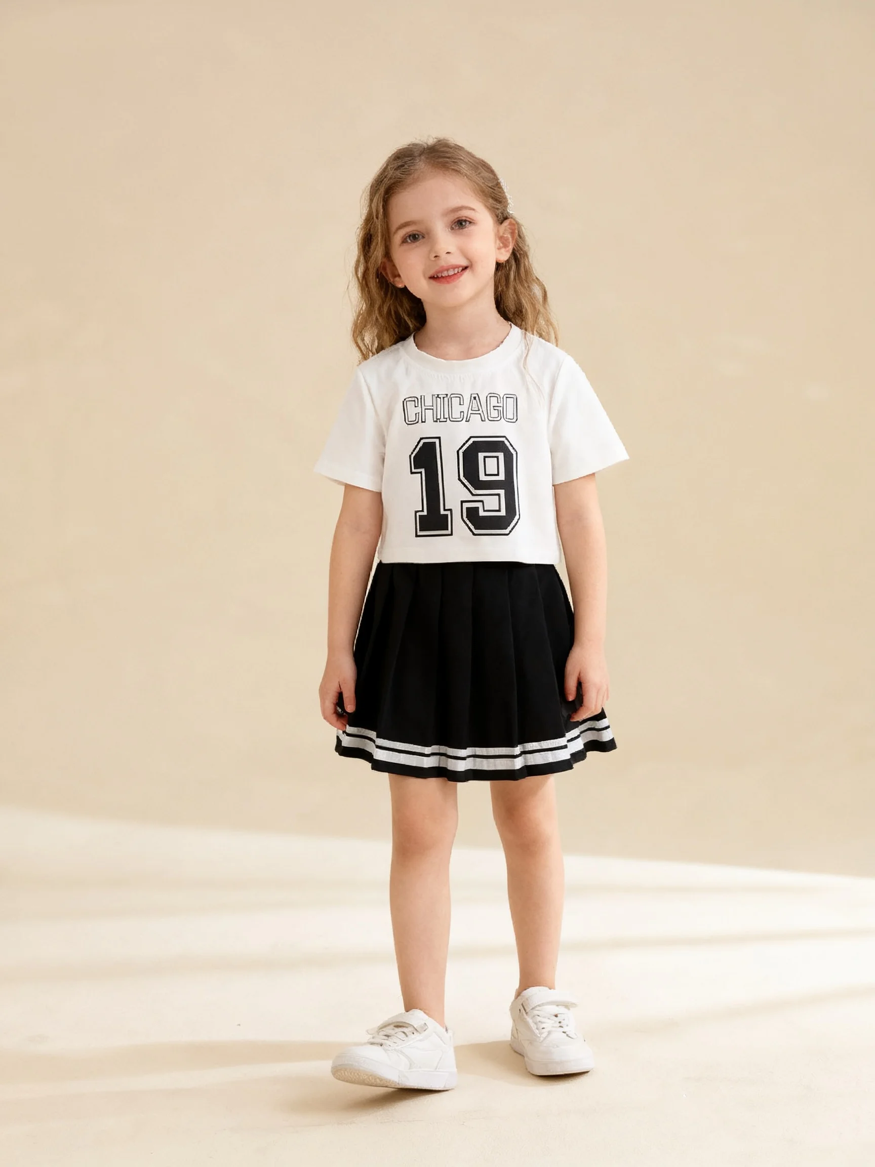 تي شيرت صيفي قصير للفتيات مكون من قطعتين برقبة دائرية ومطبوع عليه حروف بلون سادة وتنورة مطوية على طراز الكلية