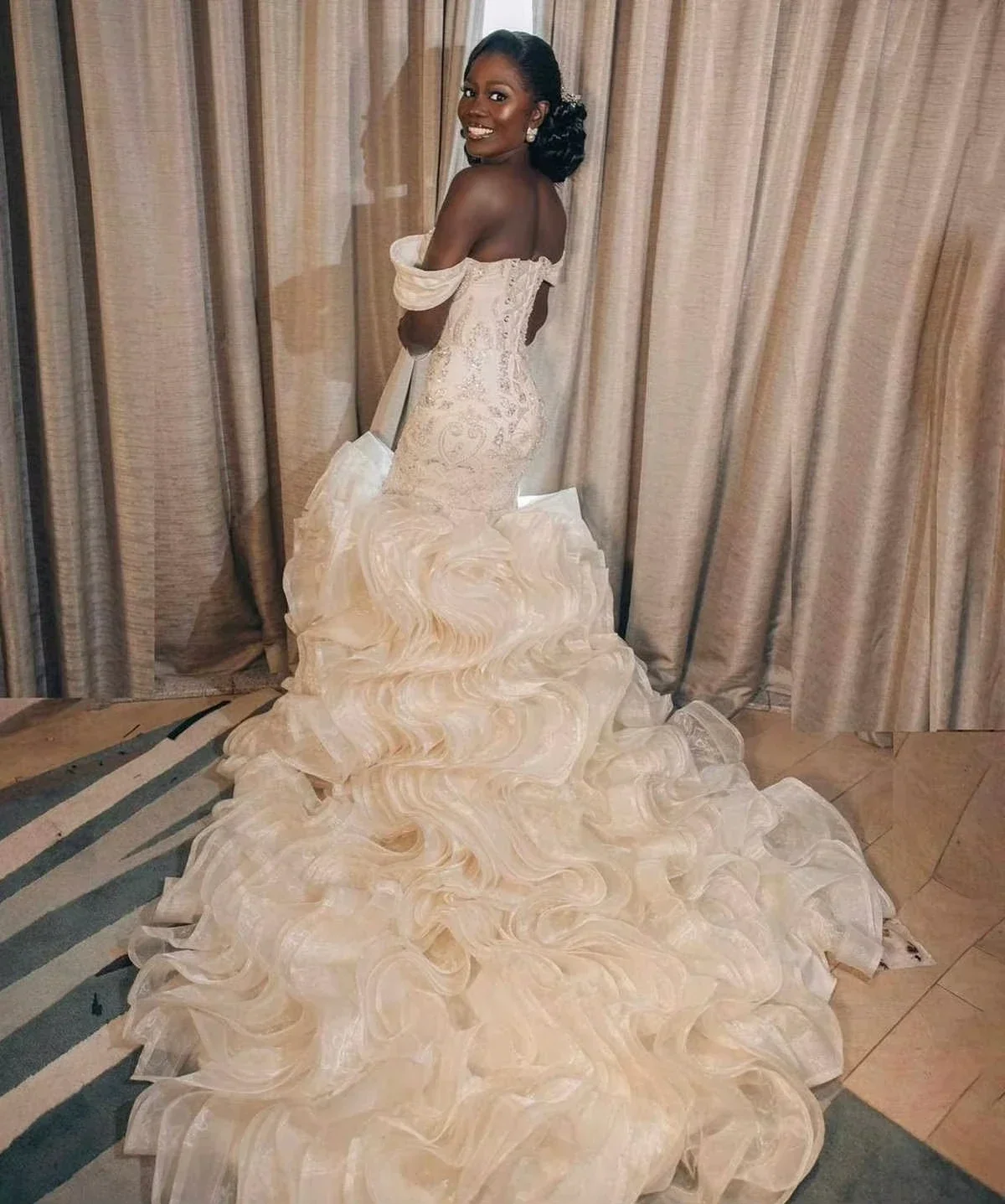 Suknia ślubna syrena z afrykańskimi, błyszczącymi perłami, z odkrytymi ramionami i kaskadowymi falbanami.