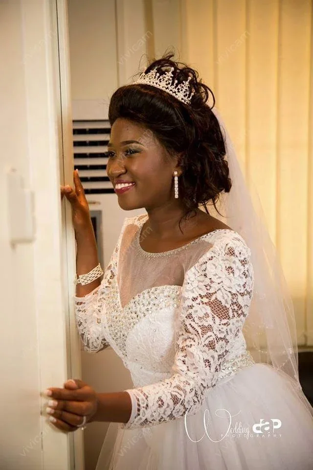 Suknie ślubne z koronką, dekoltem w łódkę, długimi rękawami, odpinanym trenem i odkrytymi plecami, zdobione uroczy, personalizowane kryształki.