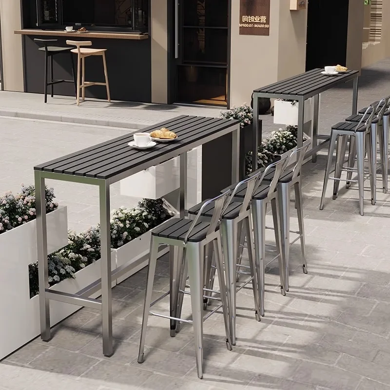 Outdoor plastic wood bar table and chairs, open-air balcony against the wall, long table bar