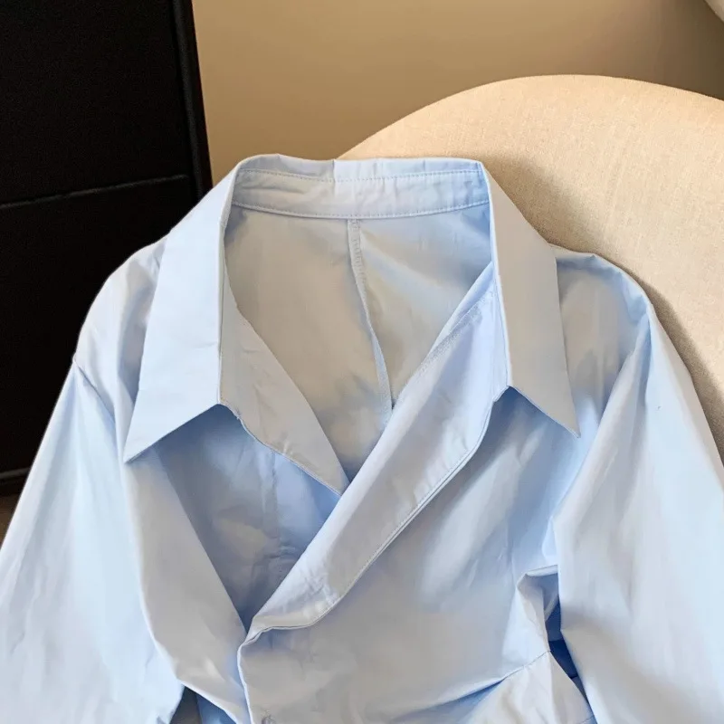 Nieregularna koszula damska z długim rękawem i klapami, biała, podkreślająca talię, minimalistyczna, podstawowa bluzka damska.