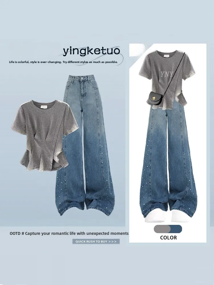 Conjunto de dos piezas estilo americano: camiseta gris de cuello redondo y manga corta para mujer, talla grande, y pantalones vaqueros azules de pierna ancha con corte irregular.