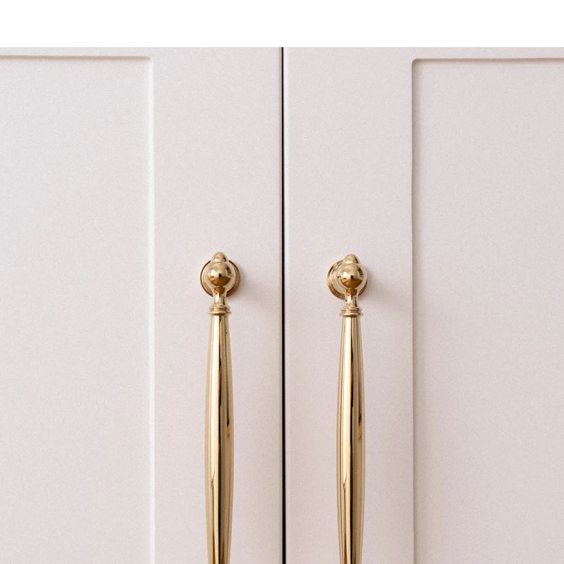 Two vertical gold handles fitted to white cupboard doors