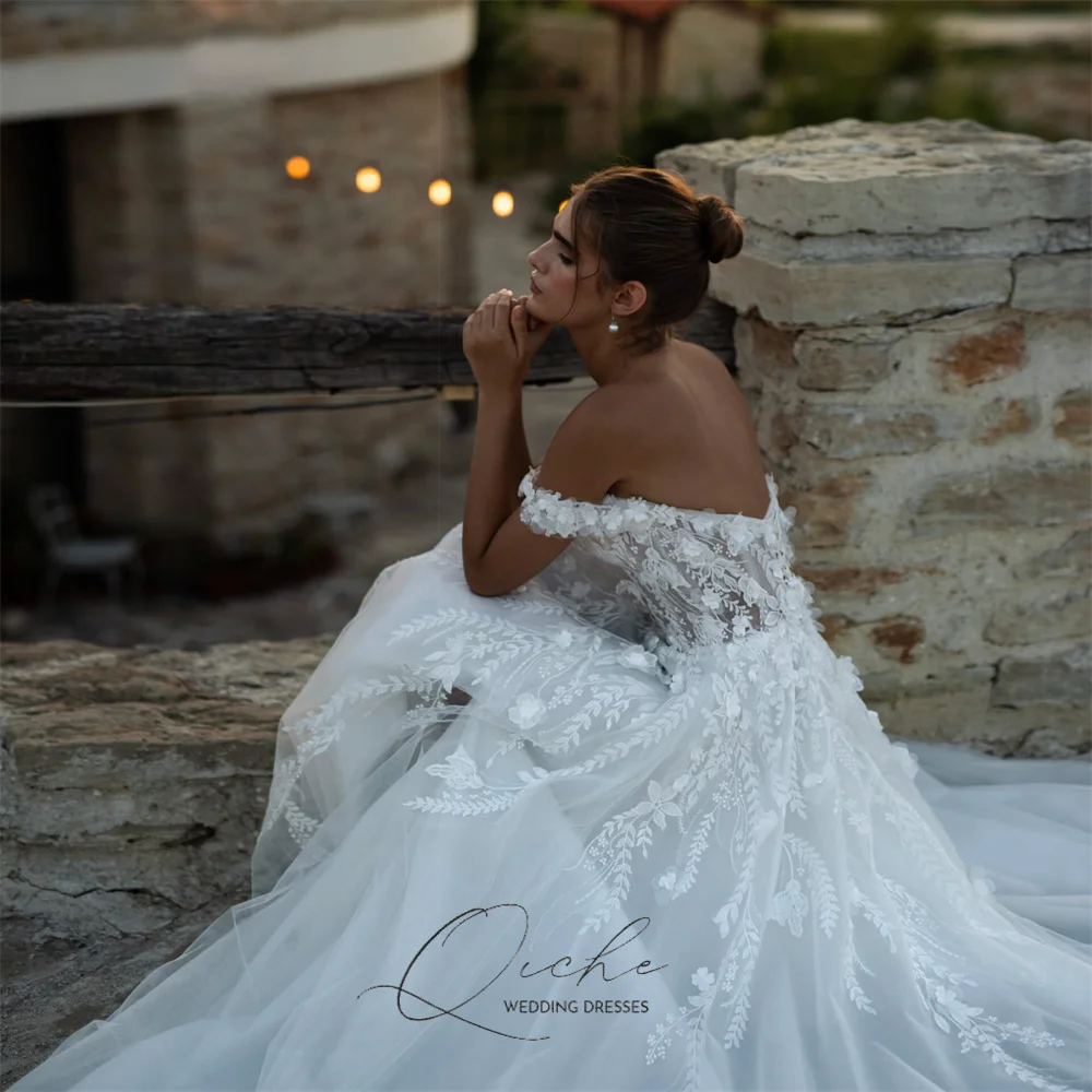 Elegancka suknia ślubna QICHE z aplikacjami z koronki, dekoltem w serek, krojem A-line, tiulowa, z odkrytymi ramionami, kwiatami 3D, rozcięciem, tiulowym odkrytym tyłem, możliwość personalizacji, kolekcja 2026.