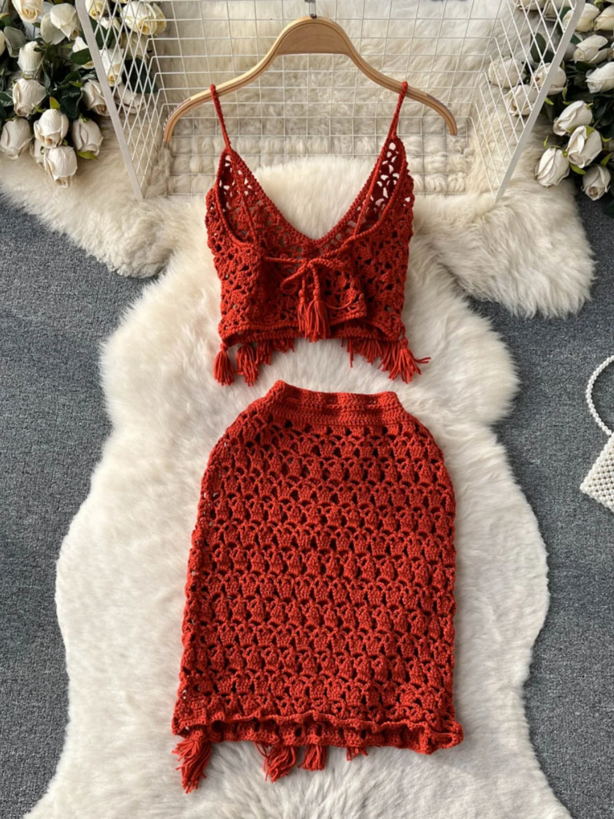 Conjunto de duas peças com top bustiê boêmio vazado com franjas e decote em V e saia curta justa, moda primavera verão fena.