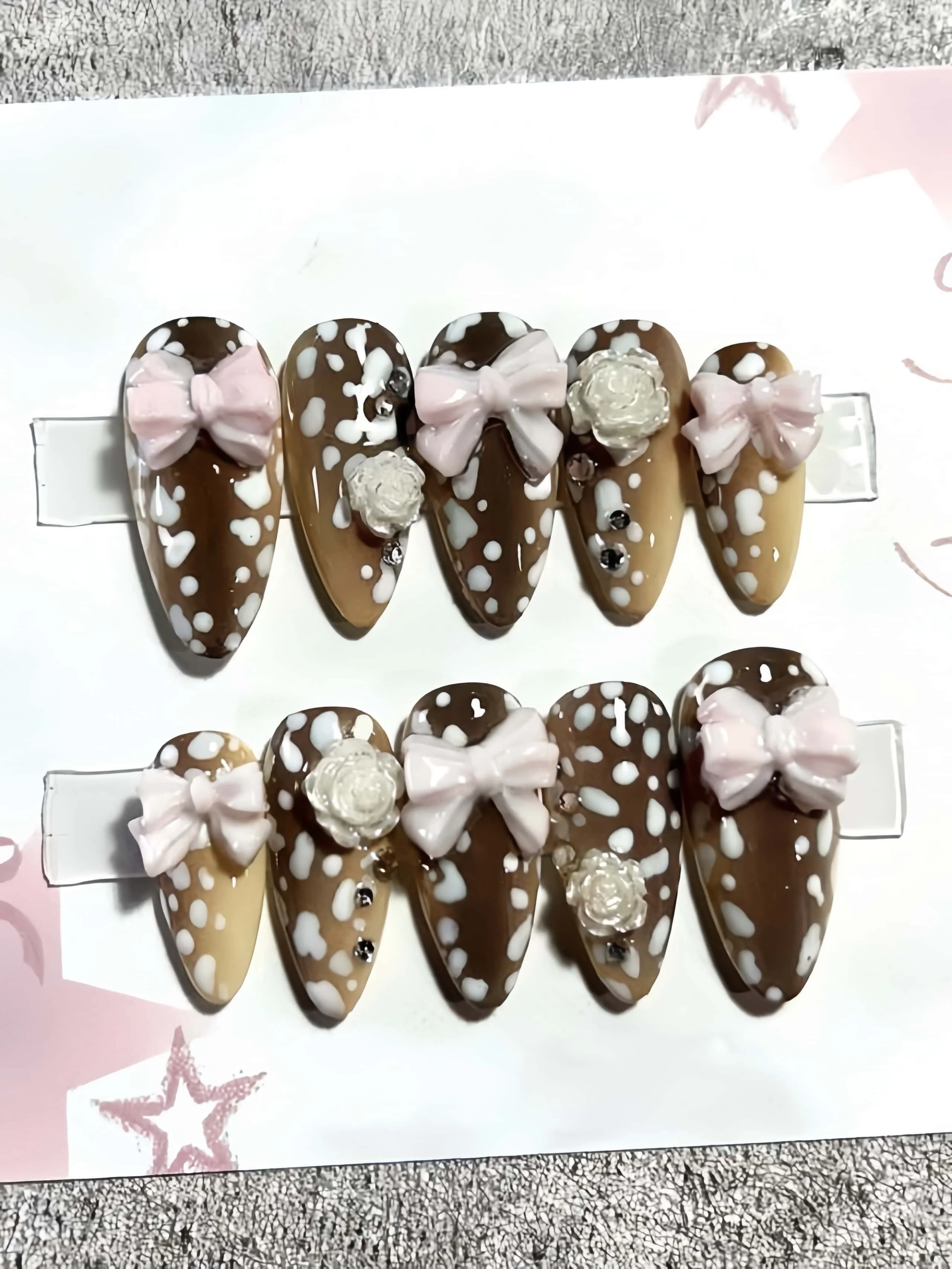 10 faux ongles faits à la main en forme d'amande, longueur moyenne, avec une base couleur café et un motif léopard blanc laiteux, accompagnés d'un nœud rose 3D et de strass roses translucides, dans un style doux et frais couleur café au lait, adaptés aux femmes et aux filles, parfaits pour les vacances d'été, la saison des diplômes et comme cadeau, livrés avec 1 pièce de colle gelée et 1 lime à ongles.