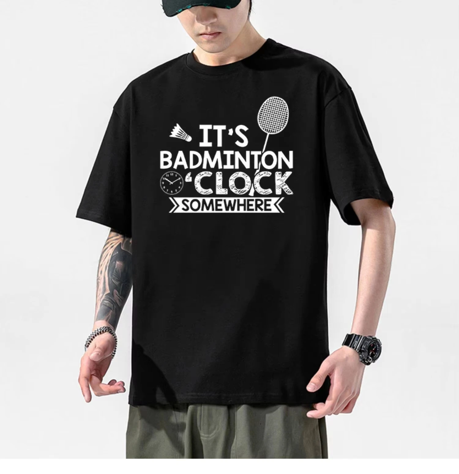 Badminton Shuttlecock - 2026年新作、ユニセックス、オーバーサイズのストリートウェアTシャツ。どこかでバドミントンが行われている時間帯をイメージしたデザイン。ラケットとシャトルコックのグラフィックが前面にあしらわれた、コットン素材のトップス。