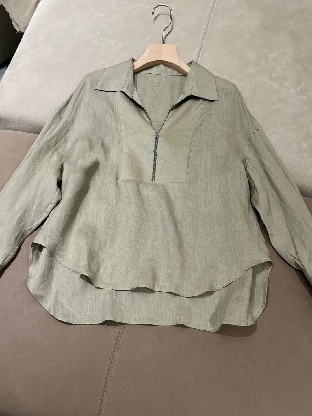 

Женская рубашка светло-зеленого цвета из драпированного льна с воротником на молнии до середины, свободного кроя.