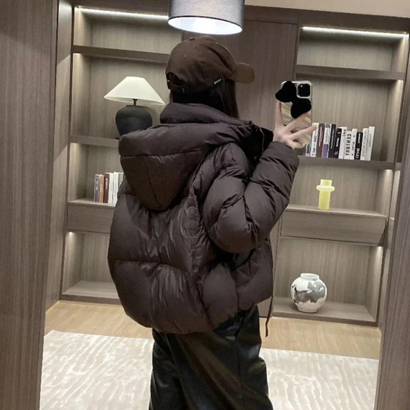 เสื้อแจ็คเก็ตขนเป็ดสีขาวสำหรับผู้หญิง เสื้อโค้ทกันหนาวแบบมีฮู้ด รุ่นใหม่ปี 2025 เสื้อแจ็คเก็ตขนเป็ดผู้หญิงทรงหลวม หนา อุ่น สไตล์แฟชั่นเกาหลี