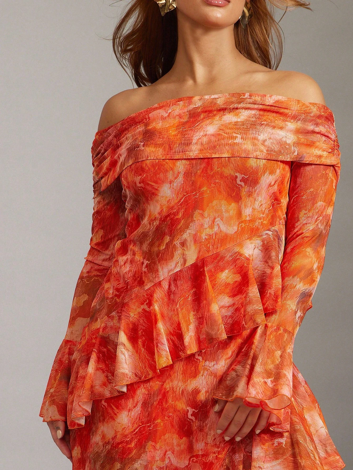 

Яркое оранжевое платье с эффектом тай-дай, открытыми плечами, длинными рукавами, многослойными оборками и асимметричным подолом