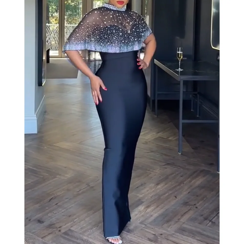 Dwuczęściowy strój: dopasowana sukienka maxi bez ramiączek z rozcięciem z tyłu na zamek i przezroczysta peleryna z siateczki z wysokim dekoltem, zdobiona cyrkoniami i perłami, zapinana na zamek z tyłu.