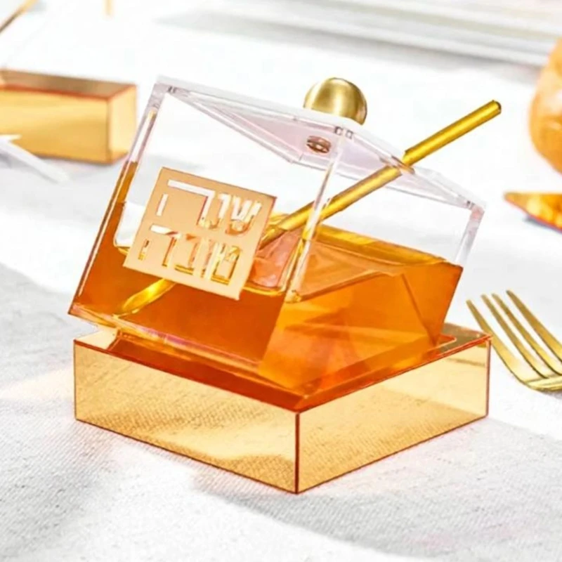 Decorative Jar for Rosh Hashanah, Clear Acrylic Container with Metallic Gold Hebrew Plaque and a Fitted Lid at the Table B03E