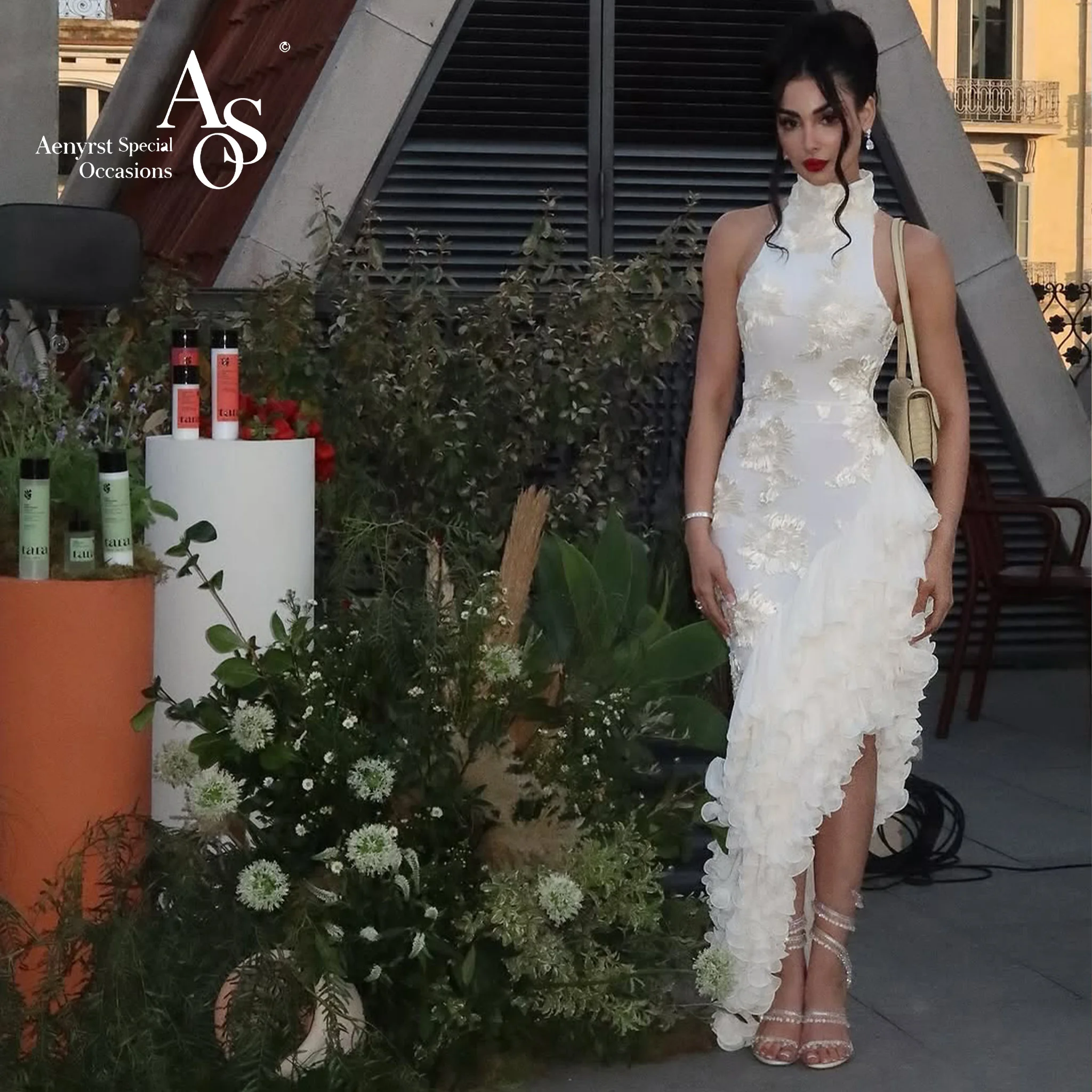 Ivory halter-neck sleeveless floor-length formal gown featuring an asymmetrical hem embroidery and a printed design
