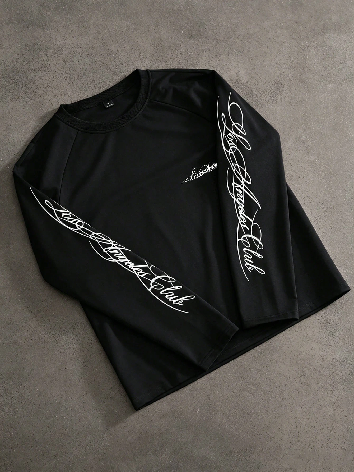 Image of West Coast Streetwear Schwarzes Raglan-Langarmshirt mit großem Kursivdruck auf beiden Ärmeln und Rundhalsausschnitt.