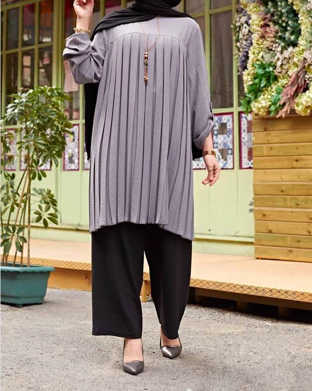 Gray pleated tunic styled with black wide-leg trousers and pointed heels