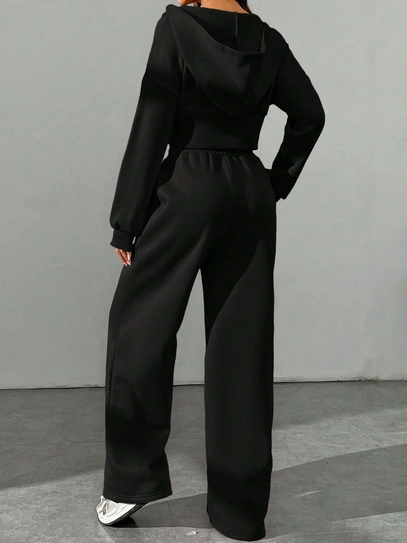 

Женский комплект: укороченный топ с капюшоном на молнии и брюки с широкими штанинами