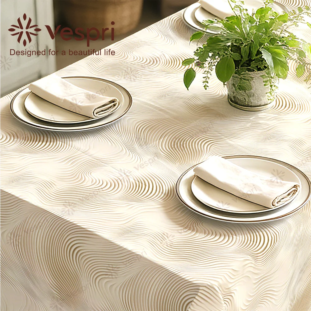 Vespri textured tablecloth, with white and beige decorations, plates and plants.