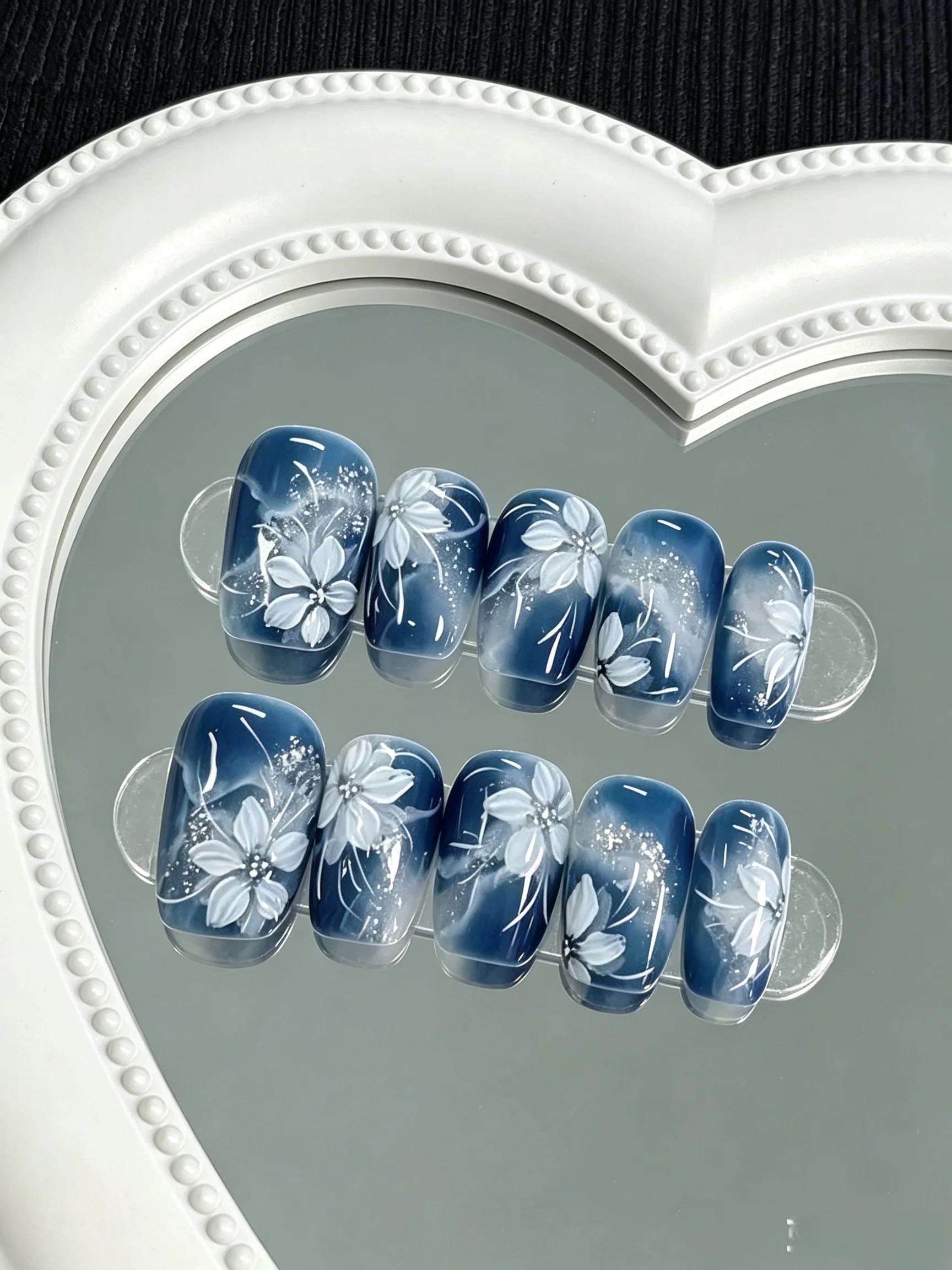 10 Pieces of Handmade Full-Cover Nail Art Tips, Medium Length, with a Smoky Blue Gradient Base Color Paired with Hand-Painted White Floral Designs and Fine Glitter Powder, Purely Hand-Painted with Delicate and Smooth Finishes, in a Cool New Chinese Style with a Gentle Vibe, Suitable for Women and Girls, Perfect for Summer Vacations, Graduation Season, and as a Gift, Comes with 1 Piece of Jelly Glue and 1 Nail File.