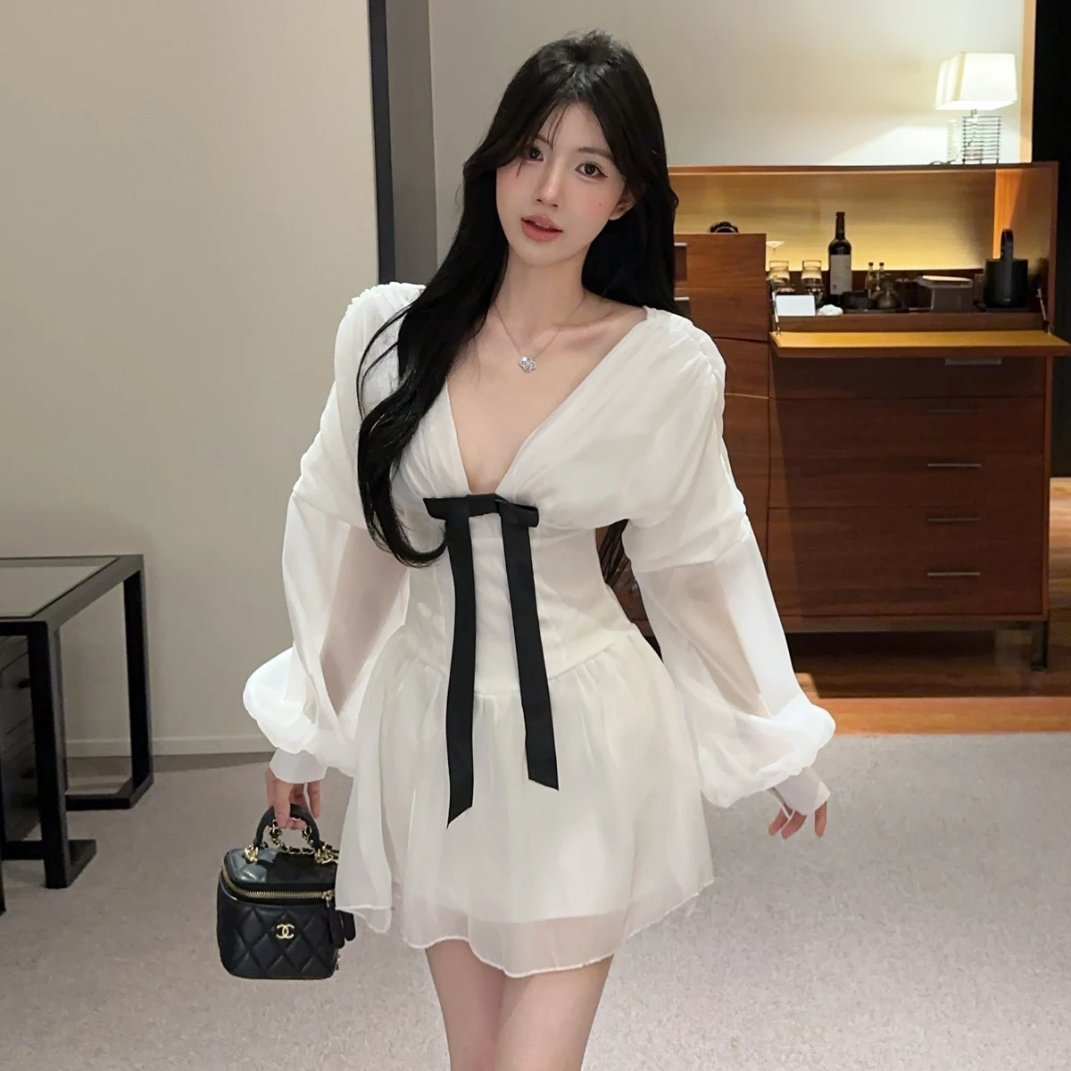 เดรสสั้นสีขาวแบบเซ็กซี่สไตล์ฝรั่งเศส คอวีลึก แต่งโบว์ แขนยาวทรงโคมไฟ ผ้าบาง โชว์เอวเข้ารูป ทรงเอไลน์ เหมาะสำหรับงานวันเกิด