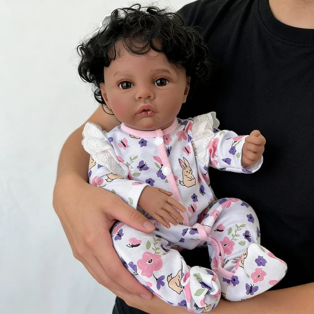 دمية طفلة رضيعة من الفينيل بطول 18 بوصة (45 سم) تشبه الطفل الحقيقي، تدعى ميدو، ببشرة داكنة، تشبه الفتيات الأمريكيات من أصل أفريقي، بشعر أسود مجعد.