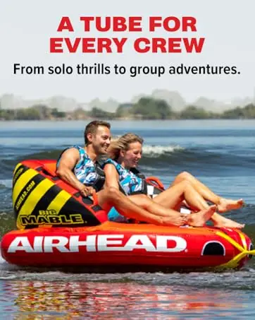 Two riders laughing on the Airhead Big Mable towable tube being pulled across a lake.