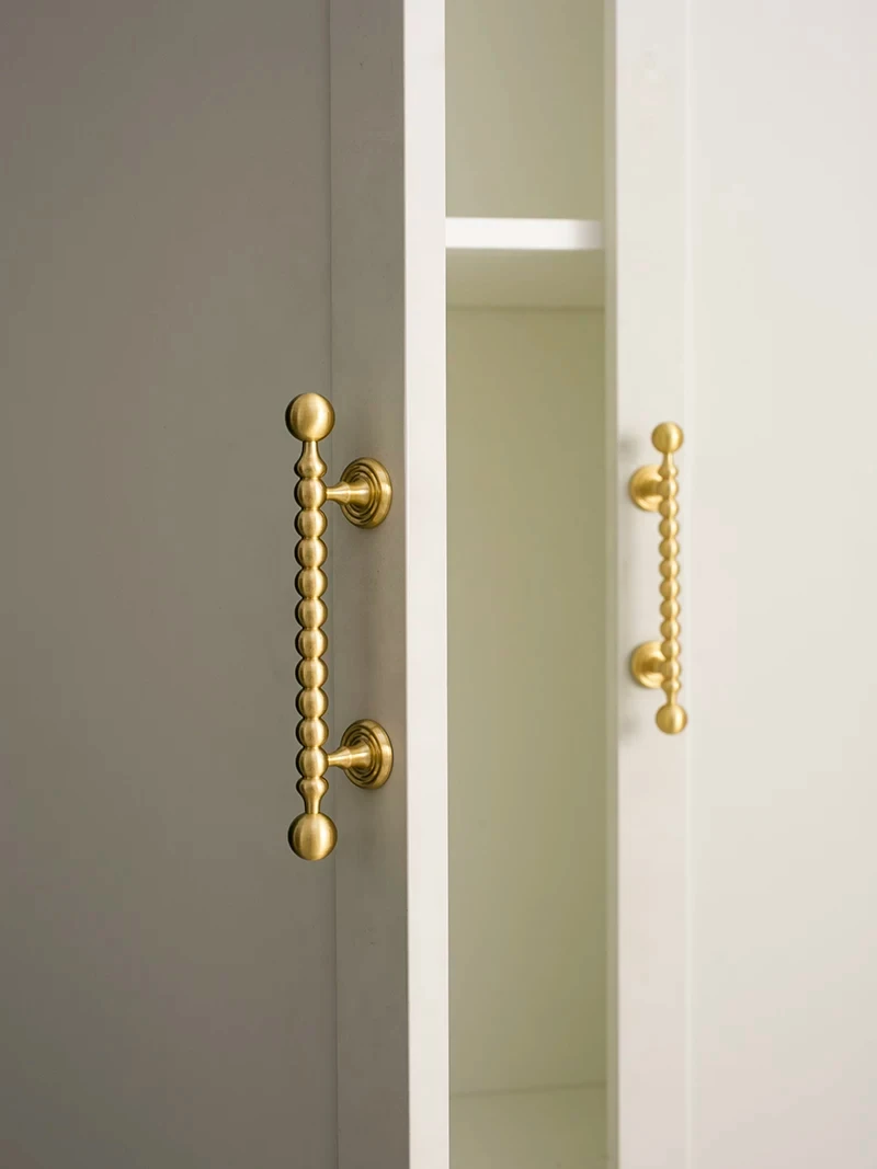 Brass beaded handle shown beside a white cupboard opening