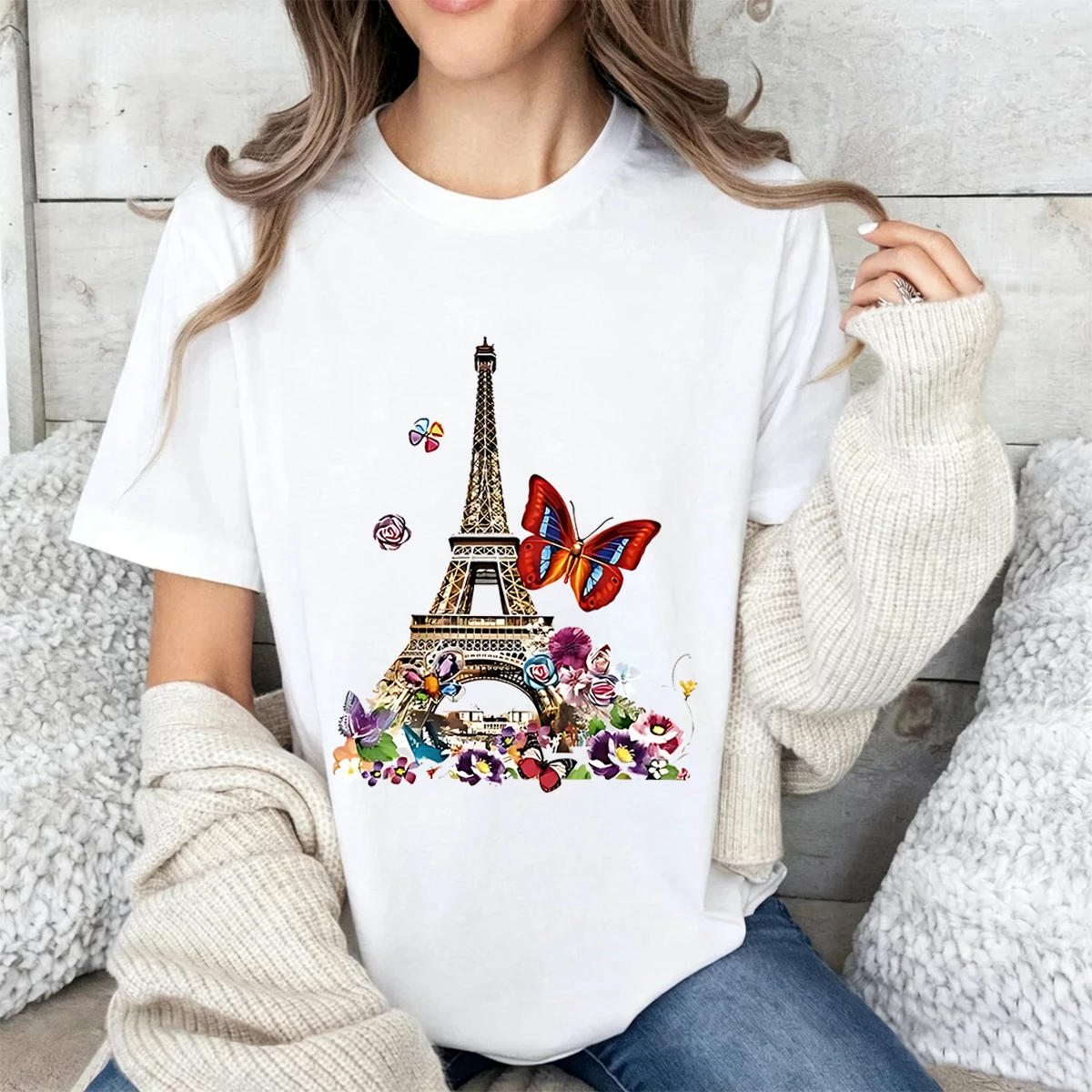 Plus-size women's cotton T-shirt featuring an Eiffel Tower, colorful butterfly, and floral print; designed with a soft, loose fit, crew neck, and short sleeves—ideal for travel enthusiasts, casual daily wear, and vacations.