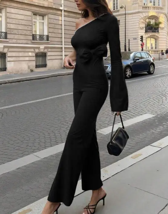 

Стильный комбинезон для повседневной носки: черный, с одним открытым плечом, асимметричным вырезом, жемчужной отделкой и свободными прямыми брюками, модель 2026 года