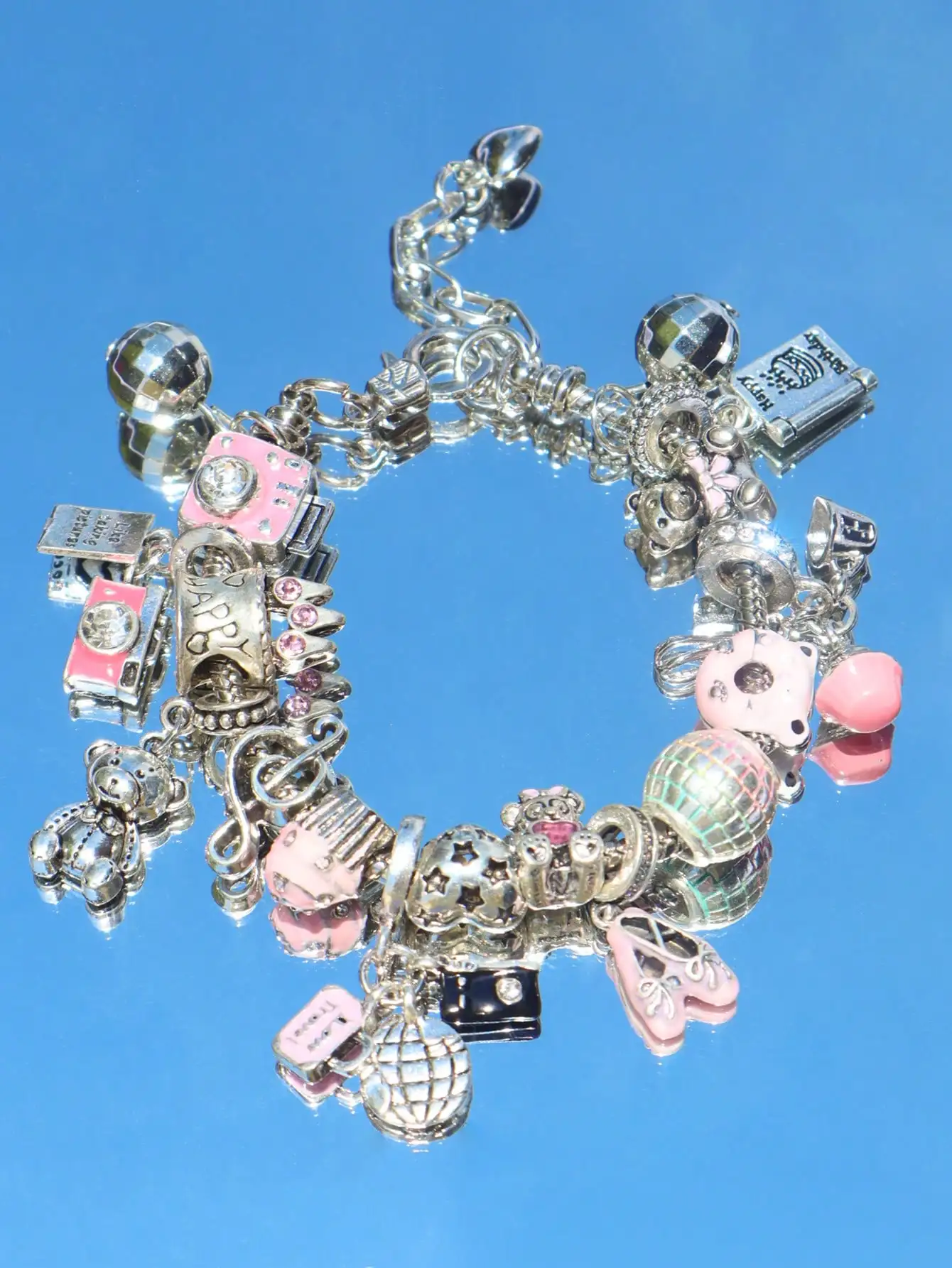 

Серебристый браслет с подвесками в виде розовой камеры, медведя, пончика и диско-шара