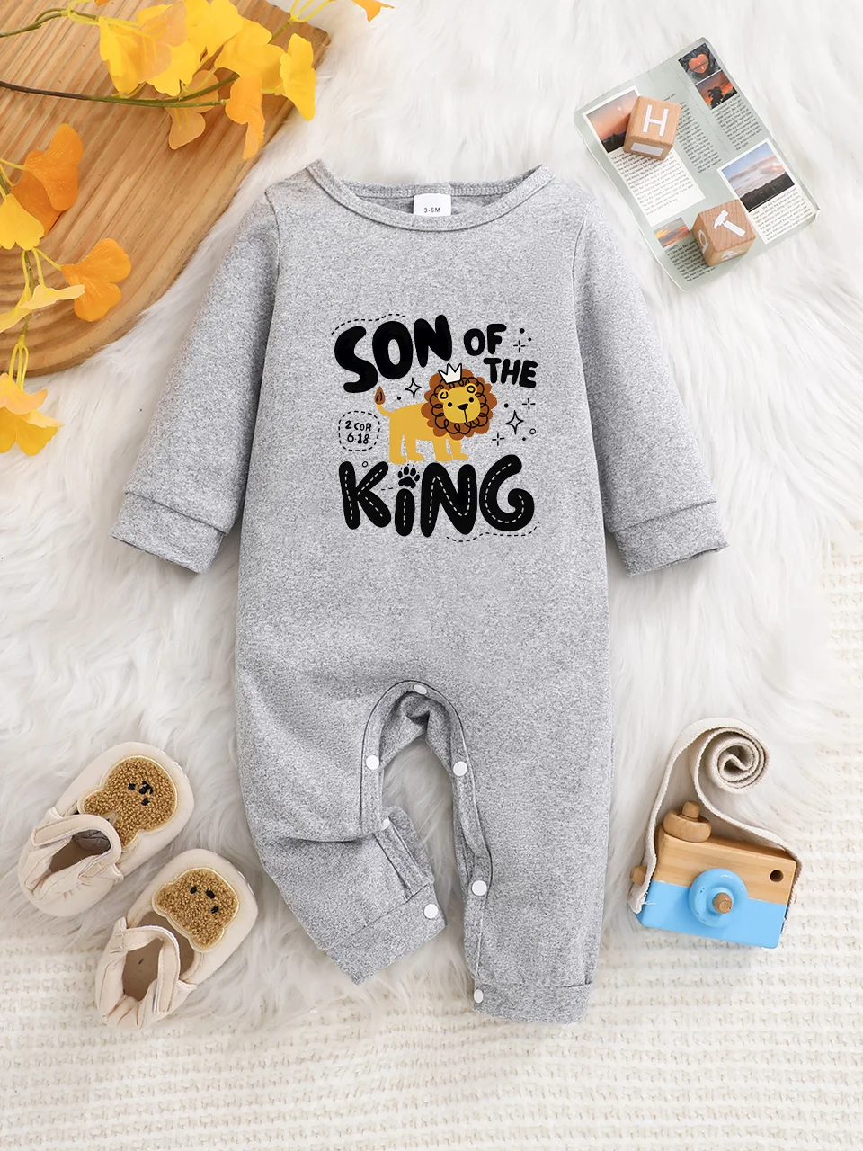 Ein langärmeliger Baby-Strampler mit interessanten Buchstaben-Prints. Es verfügt über ein Knopfverschluss-Design für einfaches An- und Ausziehen.
