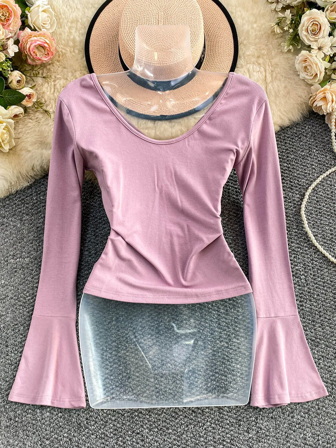 Seksowna, pikantna dziewczyna w dzianinowym, długim swetrze z dekoltem w serek, paskiem, wyszczuplającym krojem i dzwonkowymi rękawami, casualowy styl na jesień, moda damska.