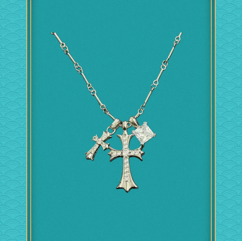 

Silver necklace with a diamond-studded floral cross and a decorative pendant