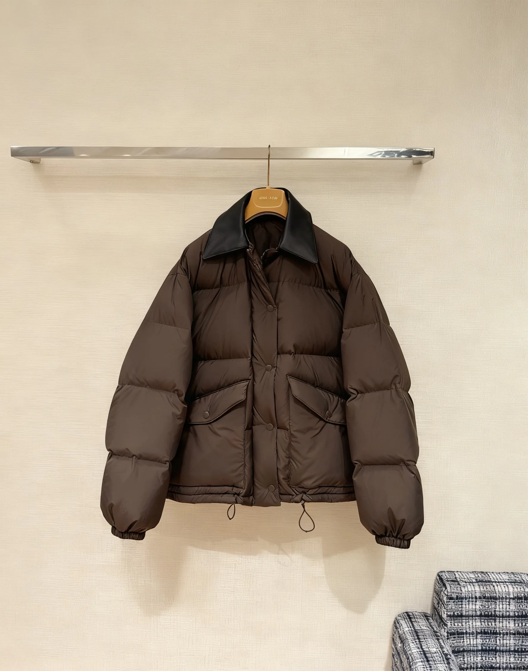 Damska kurtka puchowa w kolorze ciemnego brązu z kołnierzem ze skóry, pikowana, ciepła, z regulowanym pasem, odzież wierzchnia na zimę 2025.