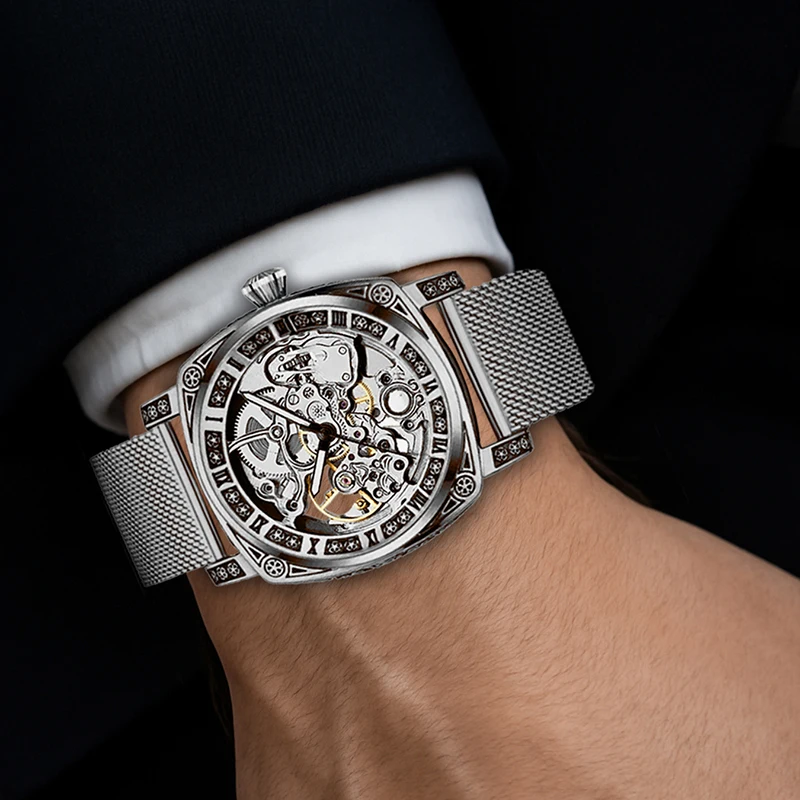 ساعة ميكانيكية أوتوماتيكية بالكامل بحزام شبكي فضي وأنيق على طراز المؤشر وأرقام رومانية للرجال.