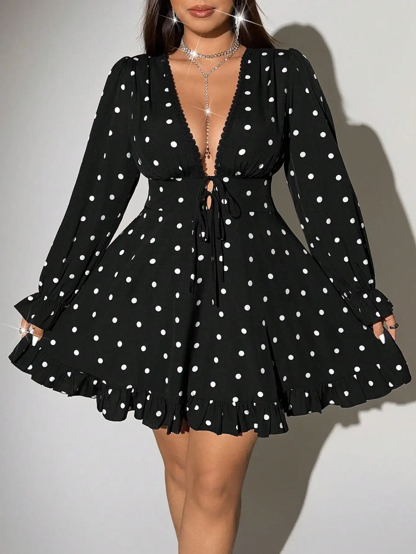 

Черное мини-платье в горошек с глубоким V-образным вырезом, рюшами по низу и длинными рукавами