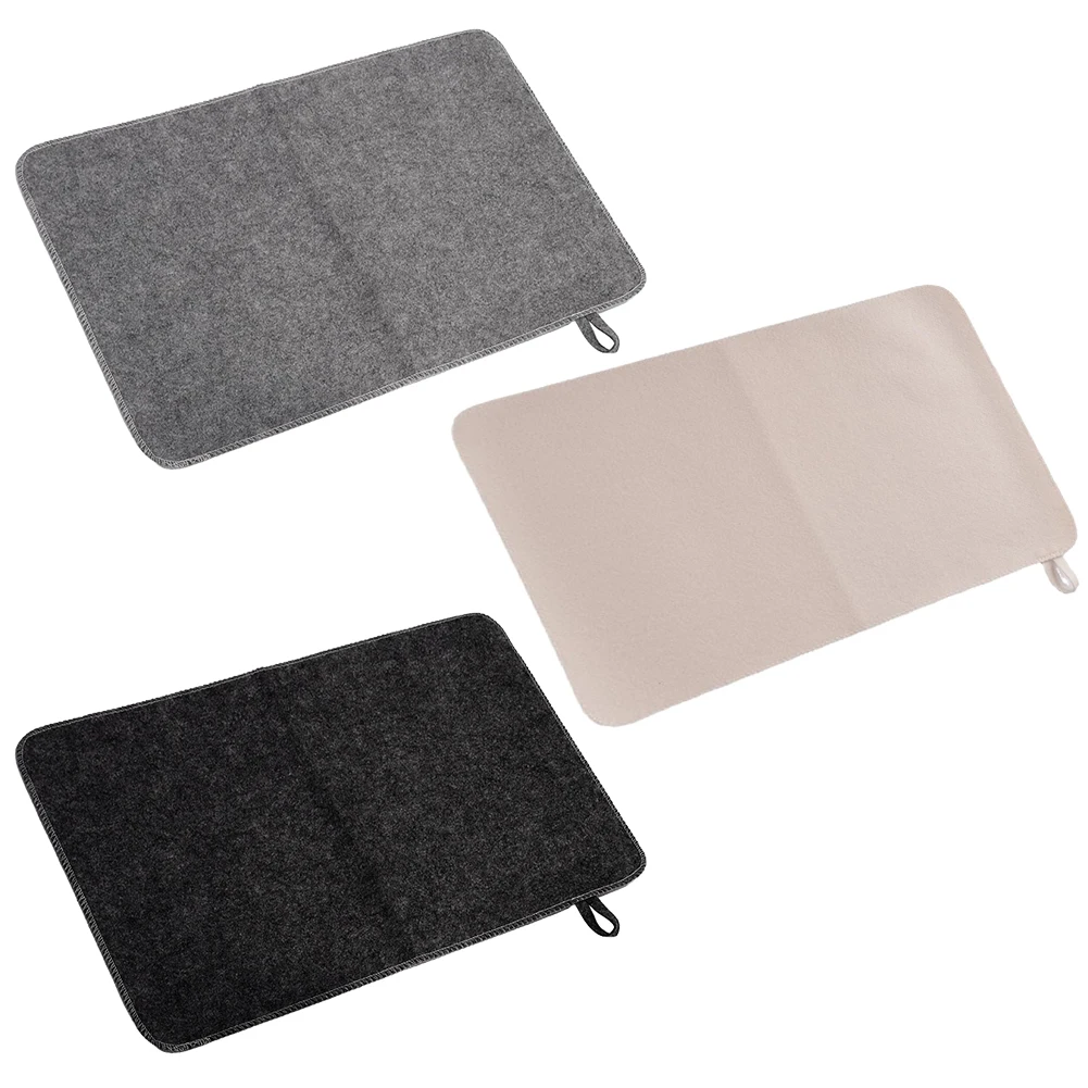 Felt sauna cushion and gray shower mat on a wooden floor with eucalyptus branches.