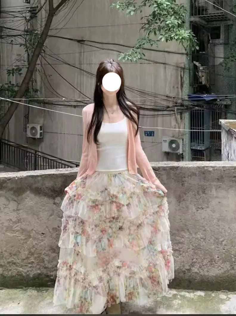 

Весенний комплект 2026: Женский розовый вязаный кардиган с открытыми плечами, юбка макси с цветочным принтом на завышенной талии и топ — Нежный стиль.