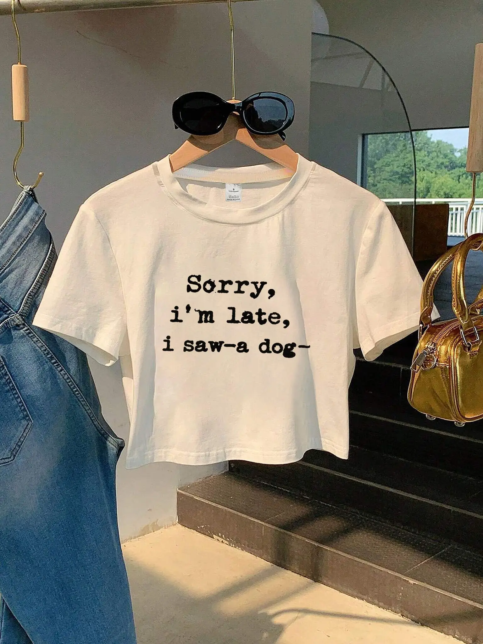 Je suis en retard, je suis allé regarder un chien. T-shirt blanc court à col rond avec texte, manches parfaites pour assortir avec des jeans bleus et un sac à main doré.