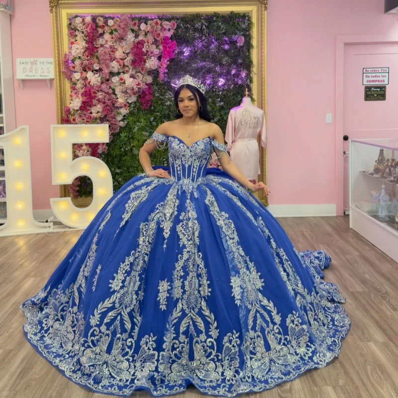 

Королевские синие платья для квинсеаньеры с открытыми плечами, серебряными пайетками, кристаллическими аппликациями, бантом и длинным шлейфом. Платье для 15-летия. Индивидуальный пошив.