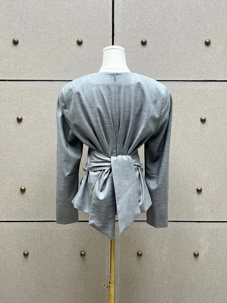 Women's cropped jacket with a crew neck, shoulder pads, and ruching; features a twisted, self-tie waist detail.