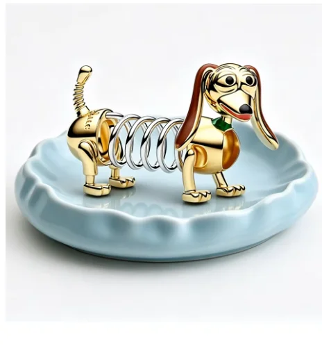 A creative two tone gold and silver mechanical spring sausage dog charm pendant displayed on a small blue decorative jewelry dish