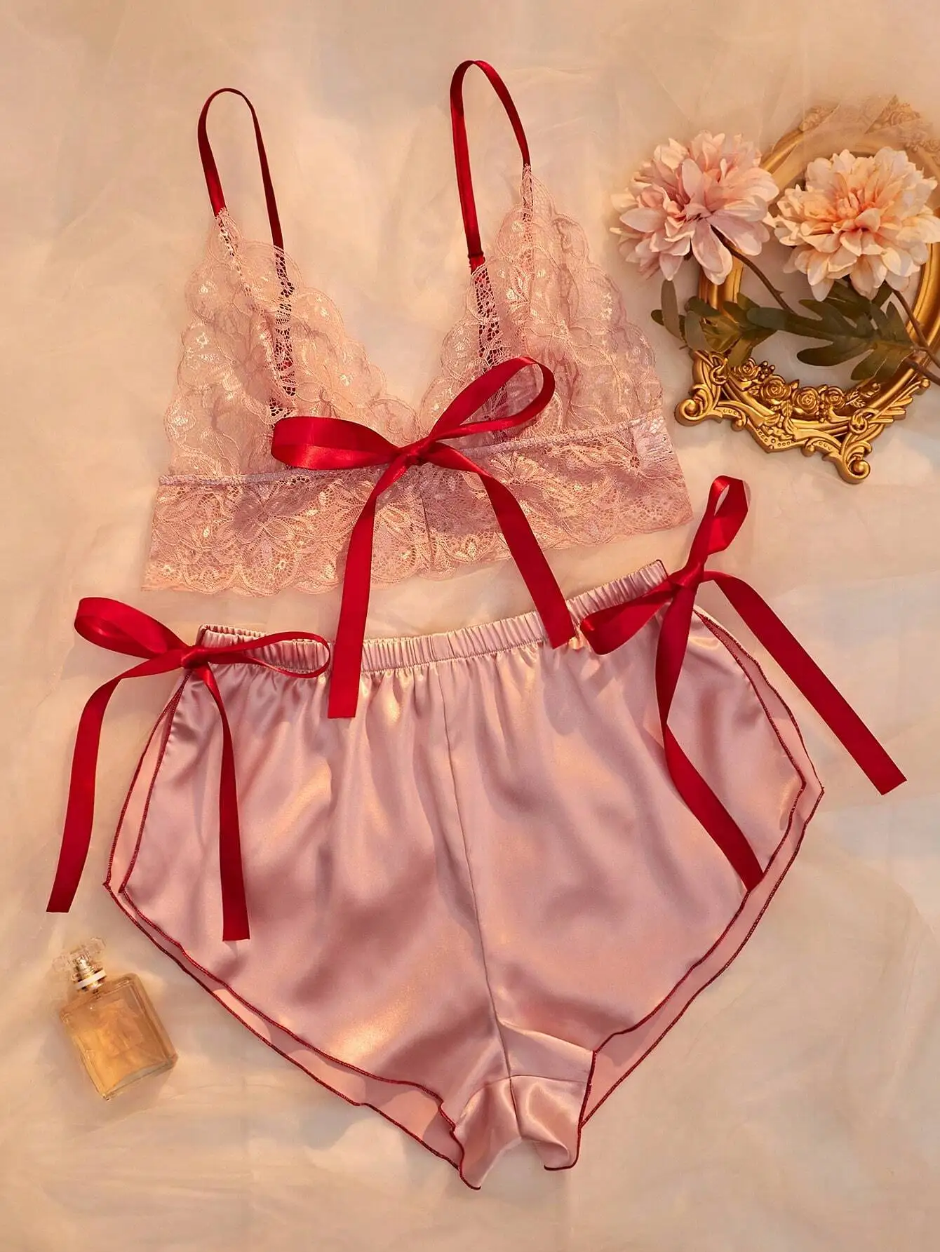 

Розовый кружевной топ-камизоль с атласными шортами, украшенный красной лентой-бантом