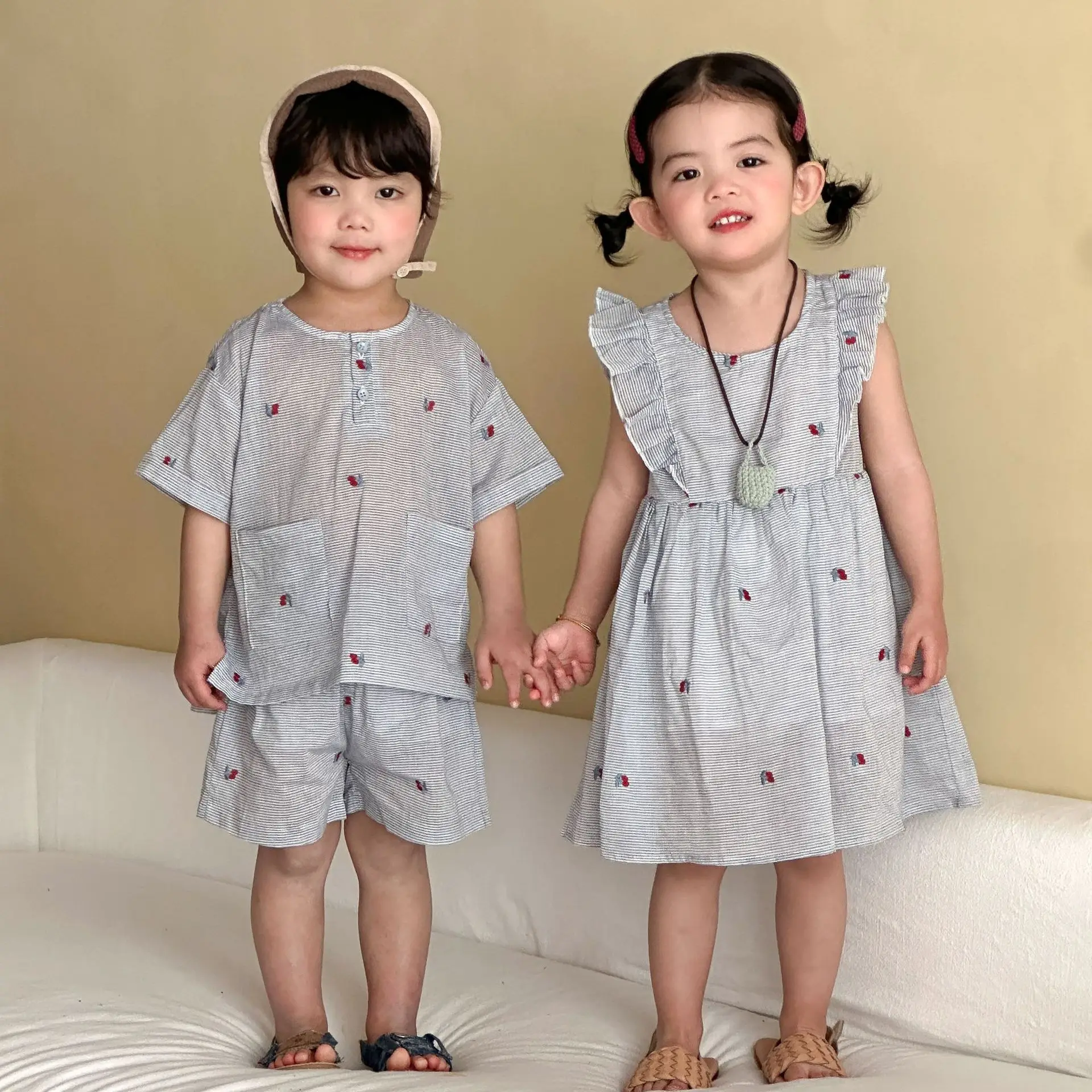 

Летняя коллекция 2026: Детская одежда для девочек (1-8 лет) – платье в тонкую полоску с рюшами и рукавами-крылышками, а также свободная рубашка для мальчиков с вишнёвым принтом