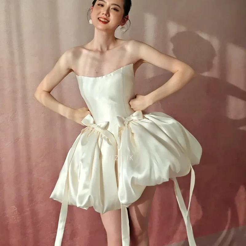 فستان زفاف قصير بسيط بيج بدون حمالات على شكل حرف a من الساتان بفيونكة قصيرة كورية لالتقاط الصور فستان زفاف مخصص للحفلات وأعياد الميلاد