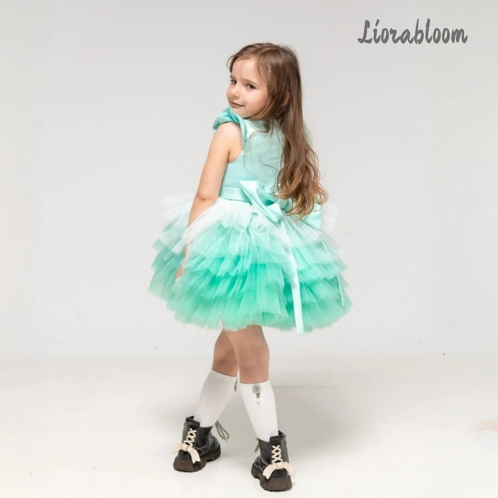 Abito da bambina verde smeraldo con gonna in tulle a balze e maniche con fiocco, ideale per spettacoli, matrimoni e damigelle.