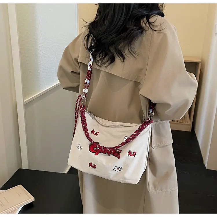 

Женская джинсовая сумка с мультяшной вышивкой, новинка 2026 года, с плетеным ремнем, повседневная сумка-хобо через плечо