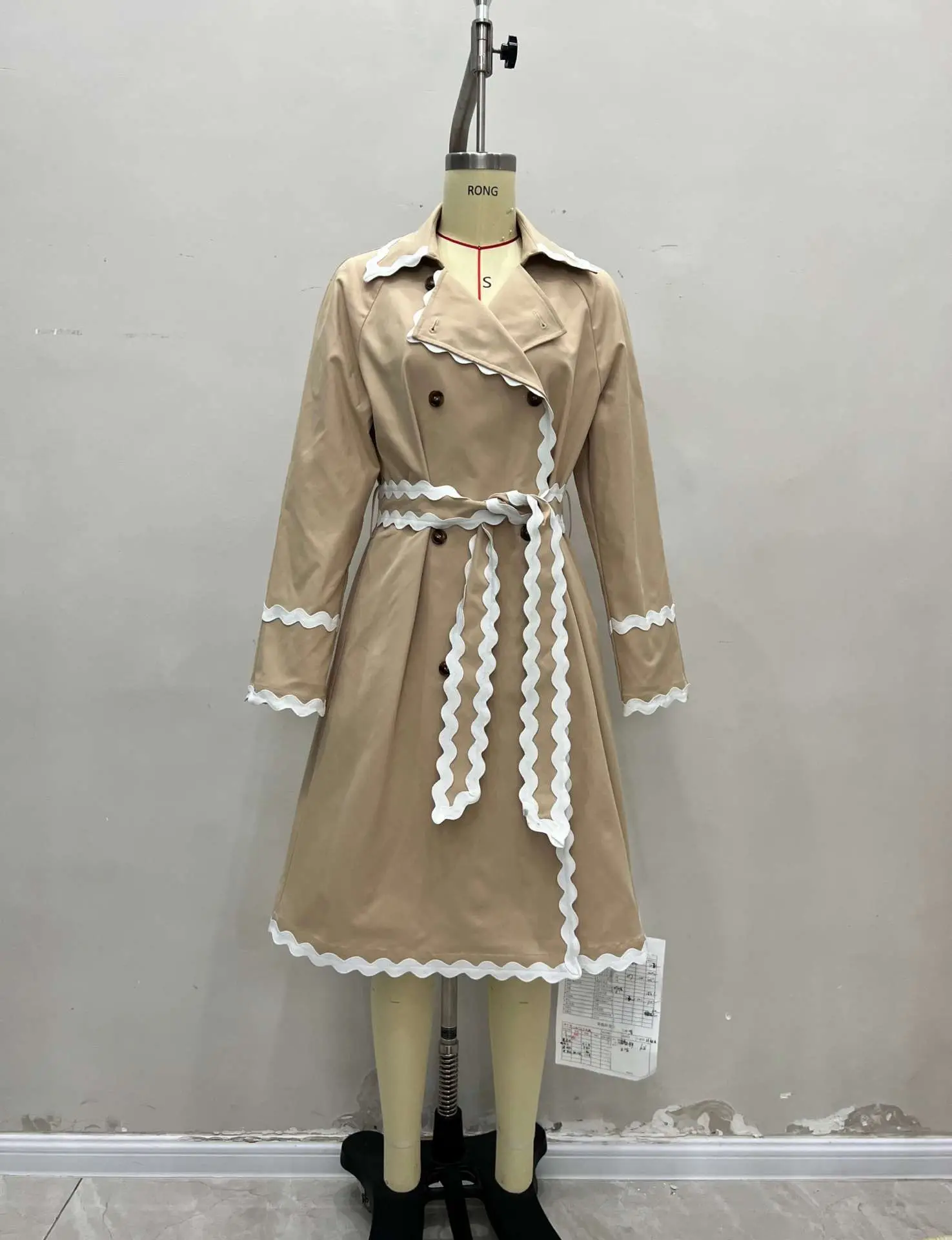 Biała marynarka z plisowanym kołnierzykiem, dwurzędowym zapięciem i podkreśloną talią oraz dwurzędowym zapięciem z przodu.